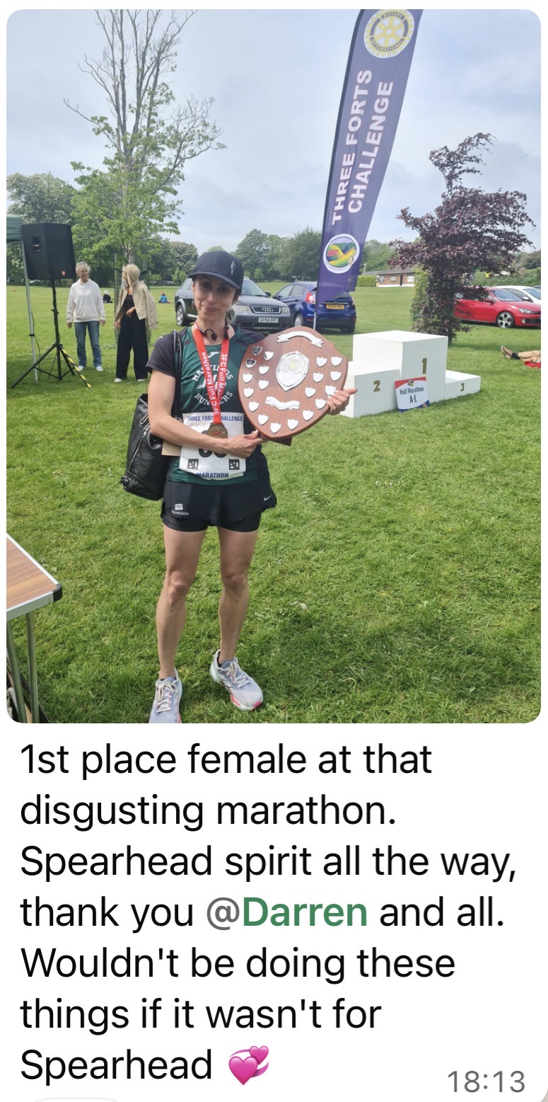 Client holding a medal & shield at the Three Forts Challenge.